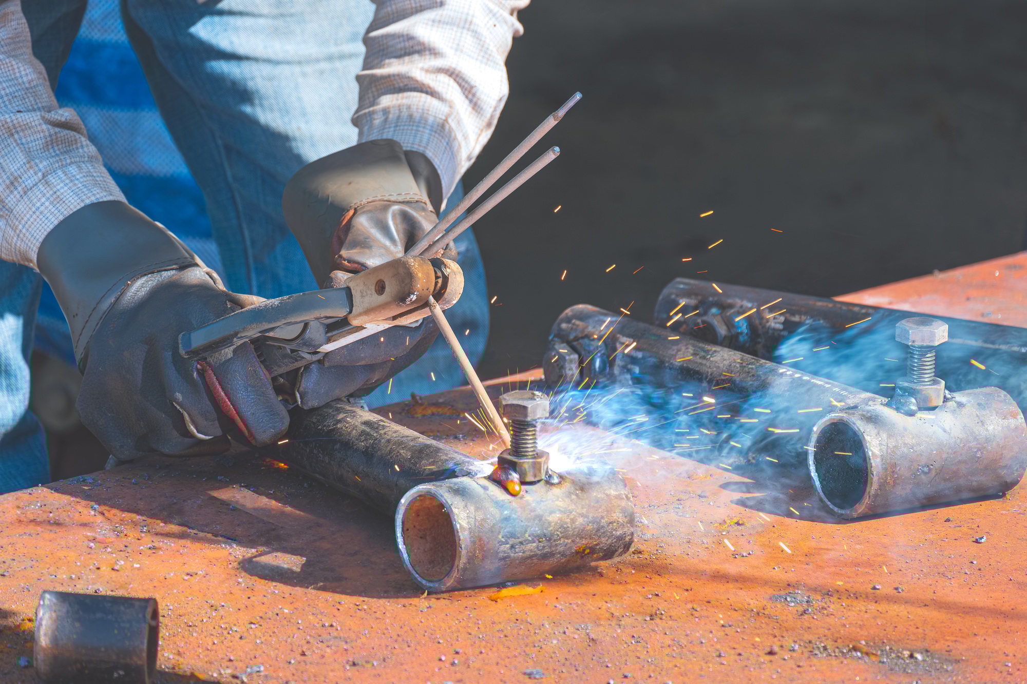 Welder hand welding nut and bolts on steel pipe for apply to metal joint in construction site area